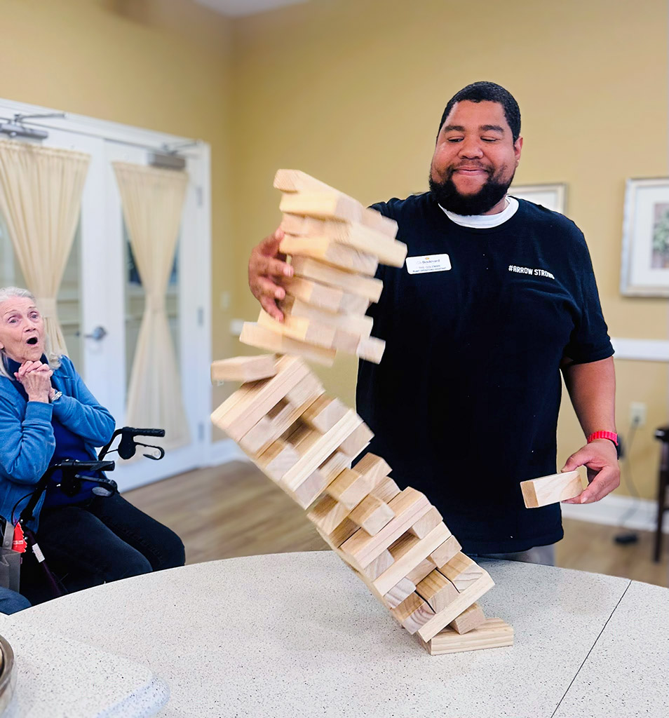Care Partner and senior resident enjoy a game together during an engaging activity inside a senior living community.