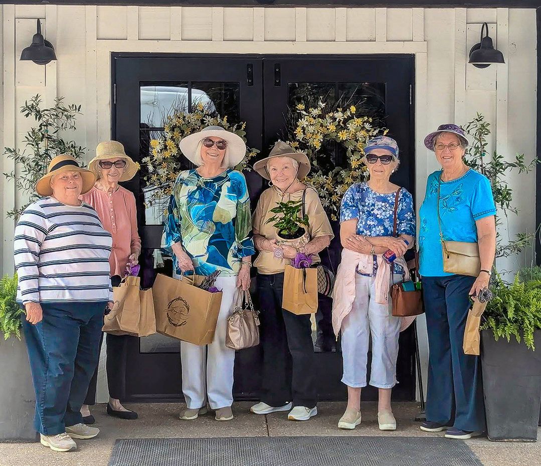 Group of senior residents pose together outside during a community outing from a senior living community.